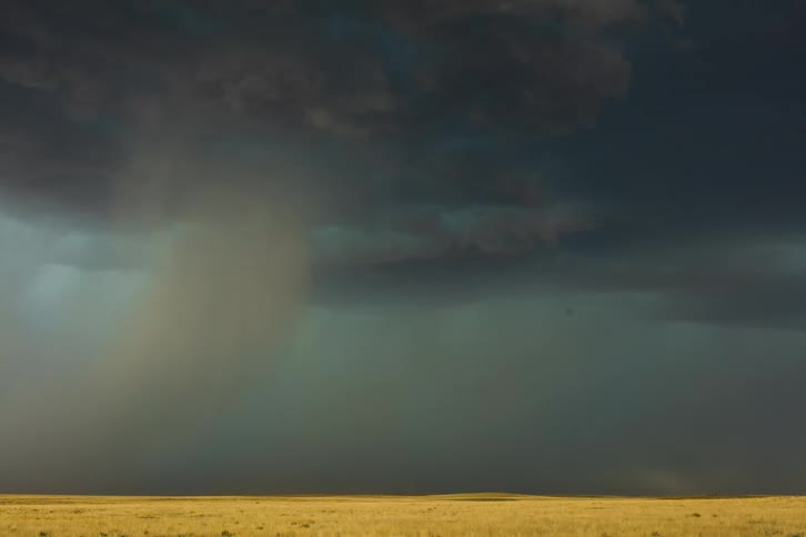 Dark clouds pour rain on rural land as lightning flashes