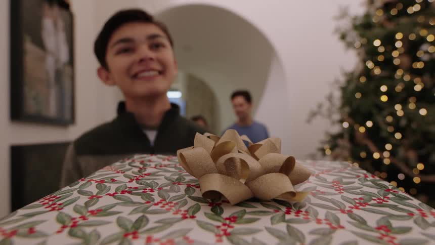 Point of view of a Christmas gift as it is being handed to a boy