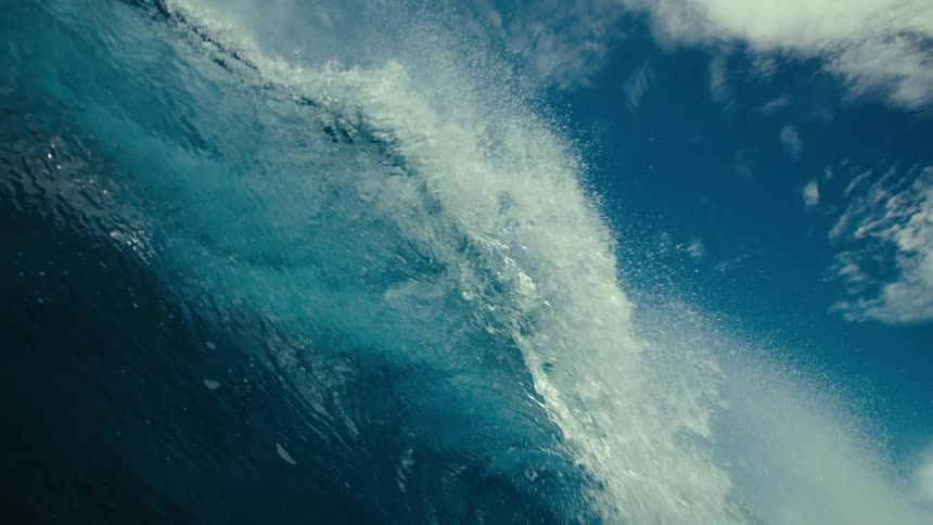 A wave covering a surfer on a sunny day