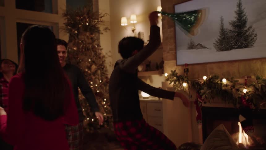 A boy spins a blue Santa hat and dances with his family at Christmas