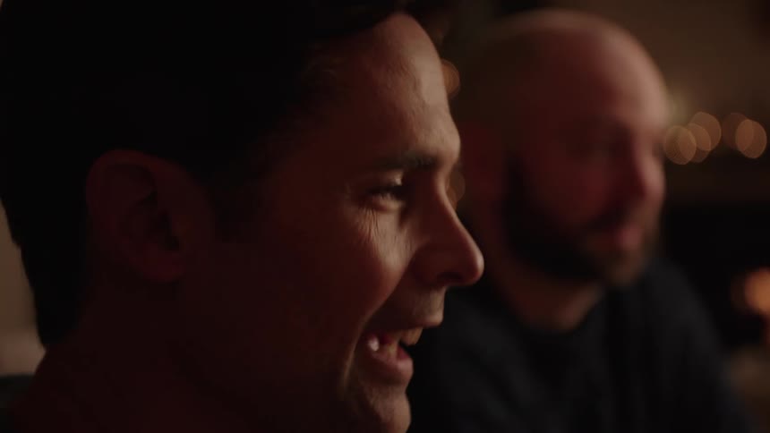 Head of a man having conversation with others while smiling indoor at night