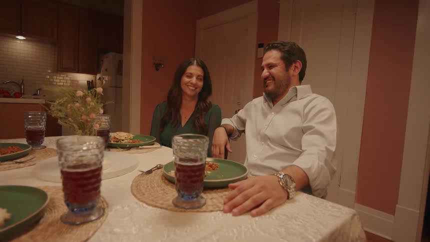 Two couples are sitting at a table talking with each other enjoying dinner and laughing