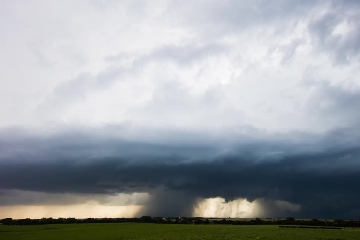 Ominous dark clouds move over a rural area as a super cell pours rain over the land