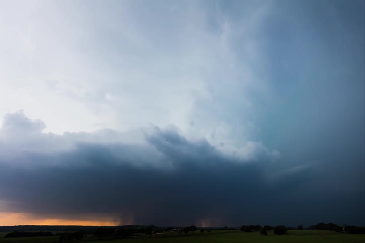 A supercell storm pours down rain as it moves across the land