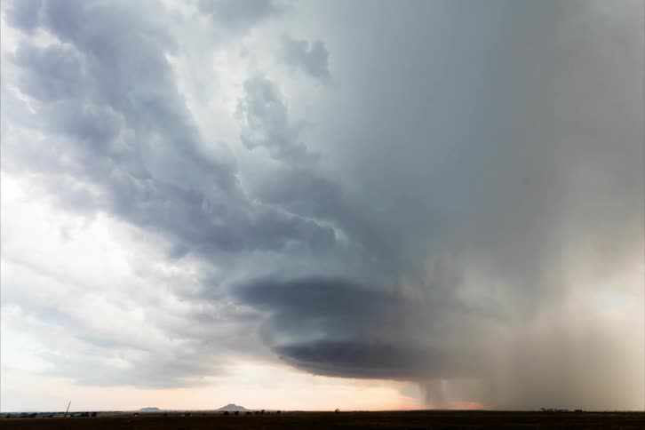 A huge cloud in the sky that is moving quickly in a circular shape