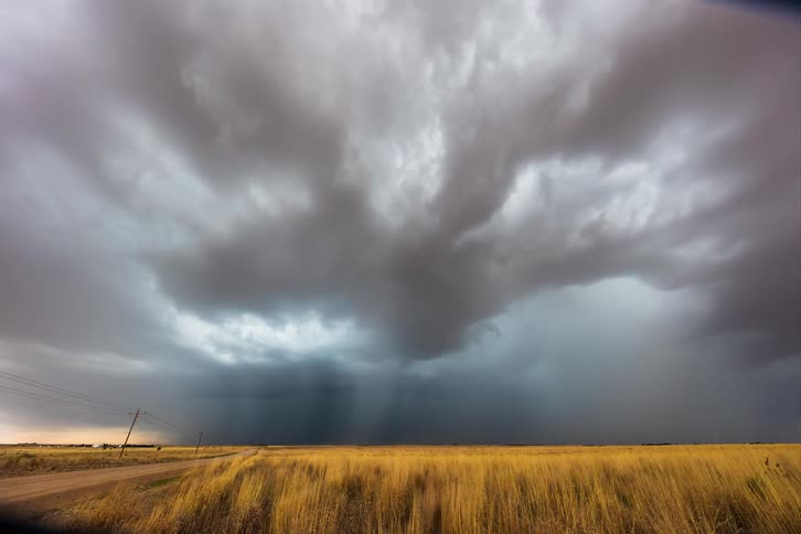 Rolling storm clouds form over the grassy plains and country road in the heartland