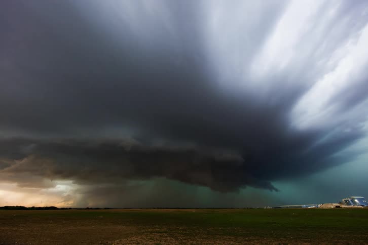 Huge supercell storm moves low over the land pouring down rain as lightning strikes