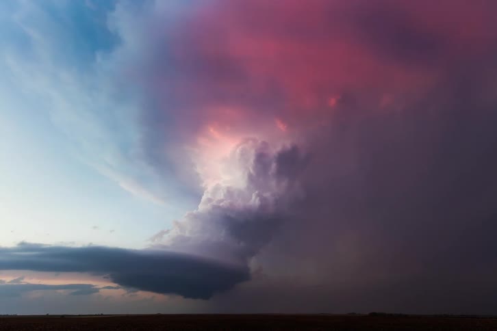 A thunderstorm in a rural field at dusk