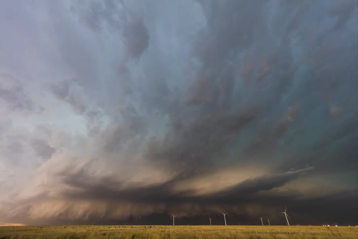 Storm clouds move in rotation over a wind farm as turbines spin
