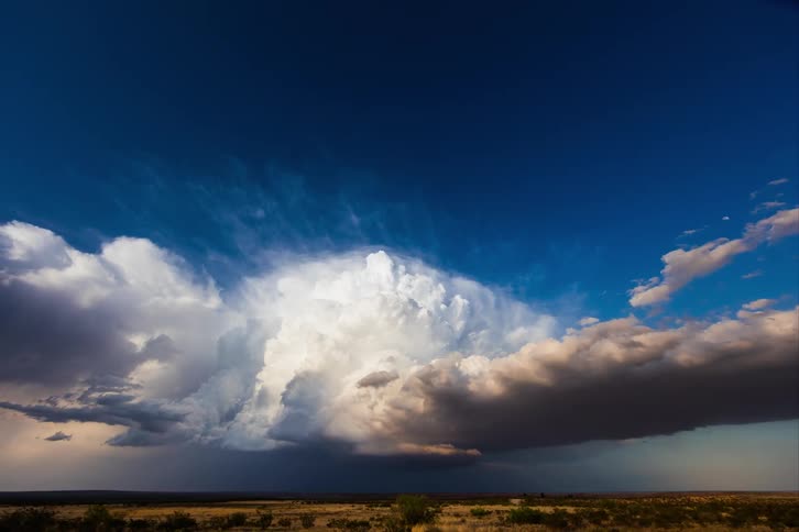 White clouds rolling under a deep blue sky over the desert