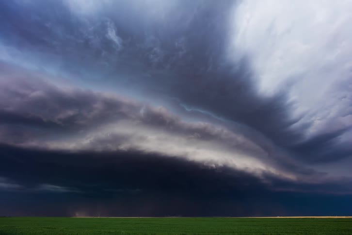 Dark clouds move over a rural area and pour down rain as lightning flashes