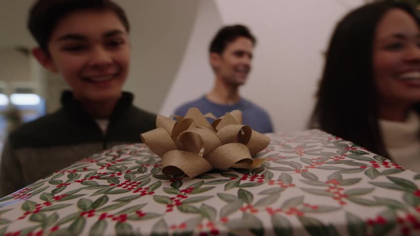 Point of view of a Christmas gift as being carried and handed to a child