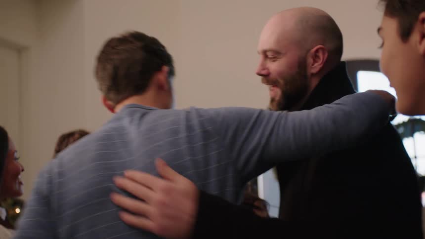 Family members meeting indoors while smiling happily at Christmastime