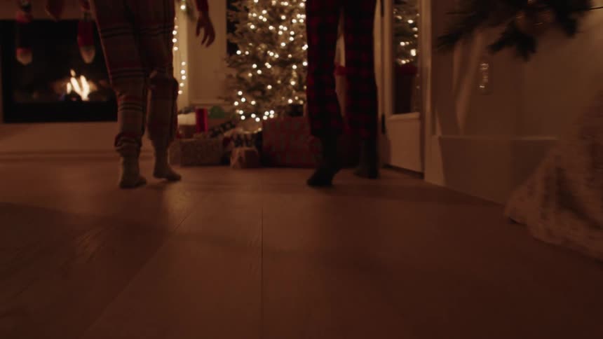 Siblings sneakily run to a Christmas tree at night to see presents