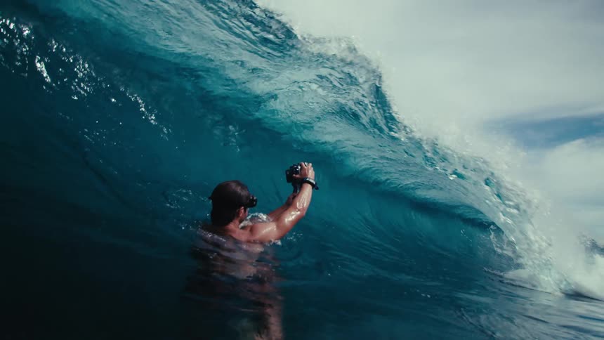 A man making video of the sea wave while being submerged underwater