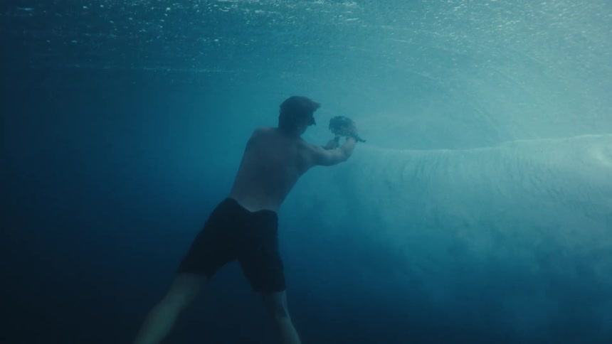 Man wearing flippers swims underwater with an underwater camera