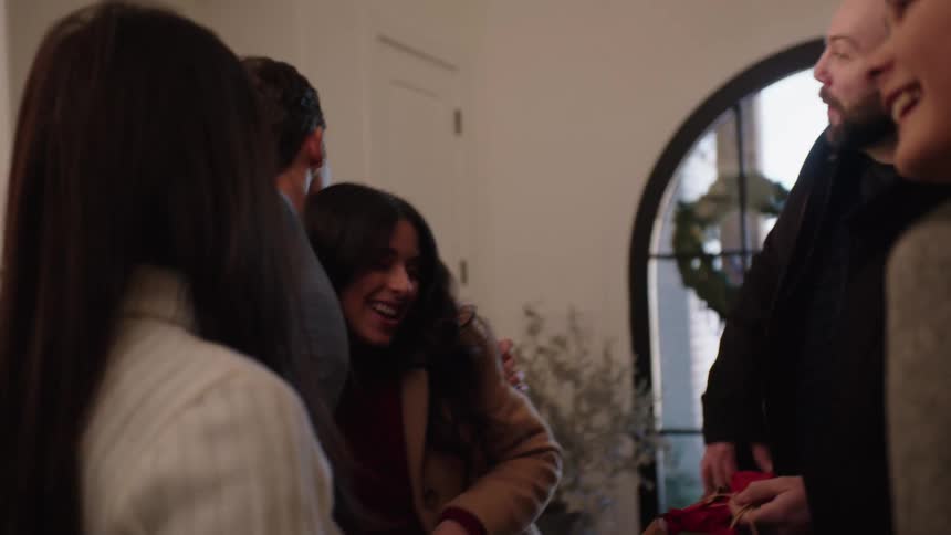 A group of friends and family hug inside a house