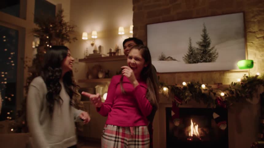A happy family dances in the living room during christmas