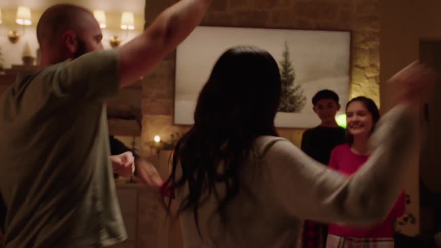 A happy family dancing in front of the fireplace