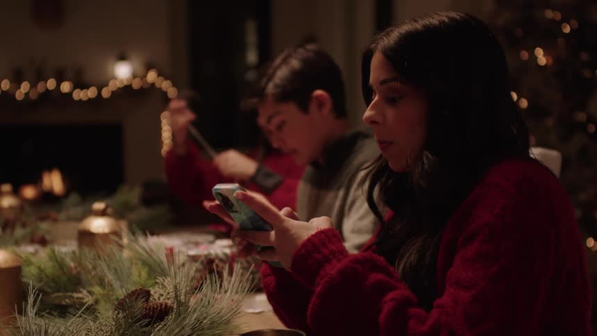 A family gathered around a table wrapping christmas gifts