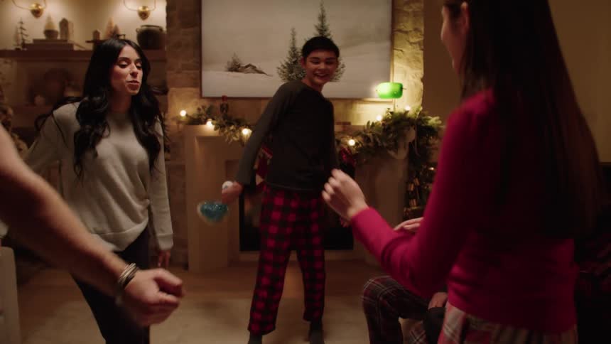 Father mother and children dancing in the living room while smiling at night