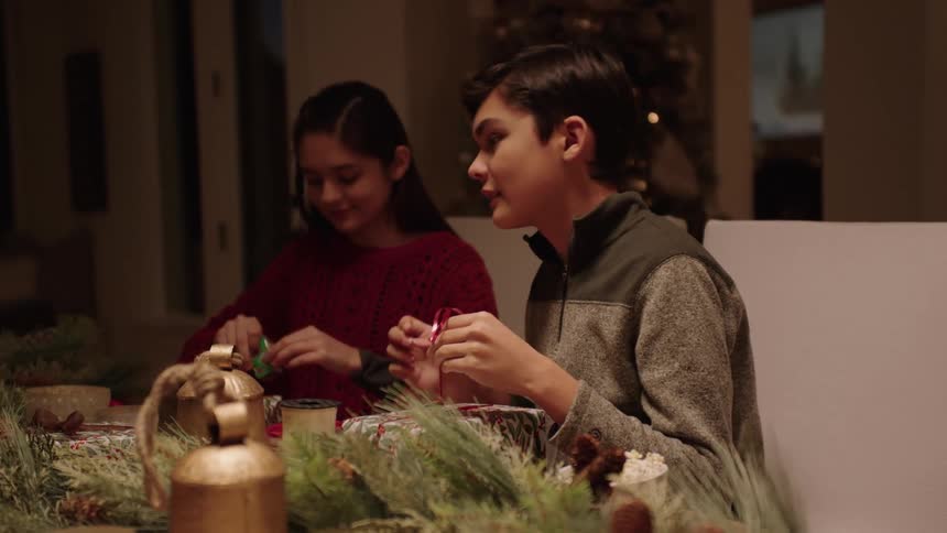 A boy and a girl wrapping the familys christmas presents