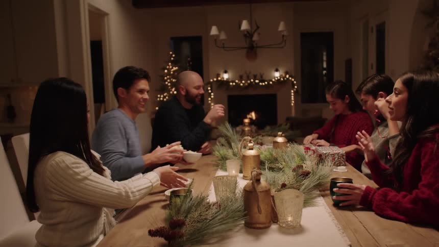 Family gathers around the table at christmas to celebrate together