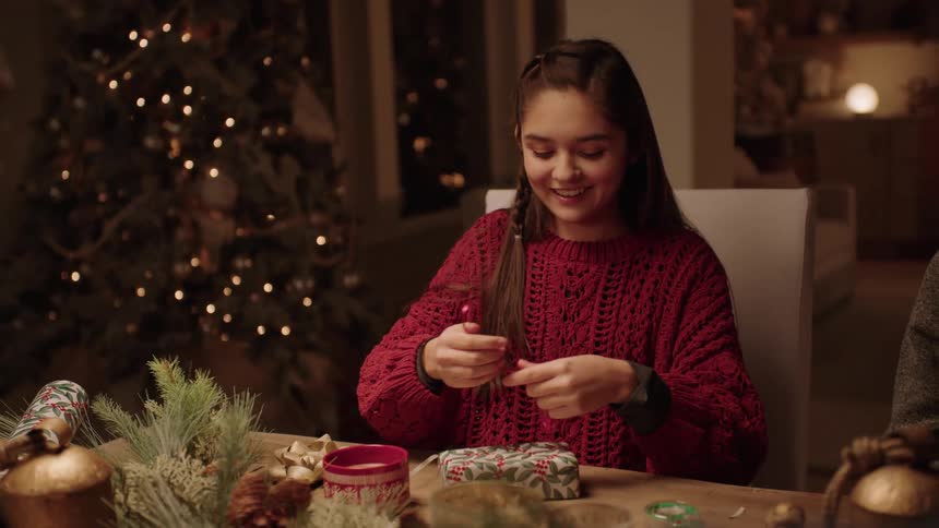 Teenage girl has fun wrapping gifts with the family at christmas night