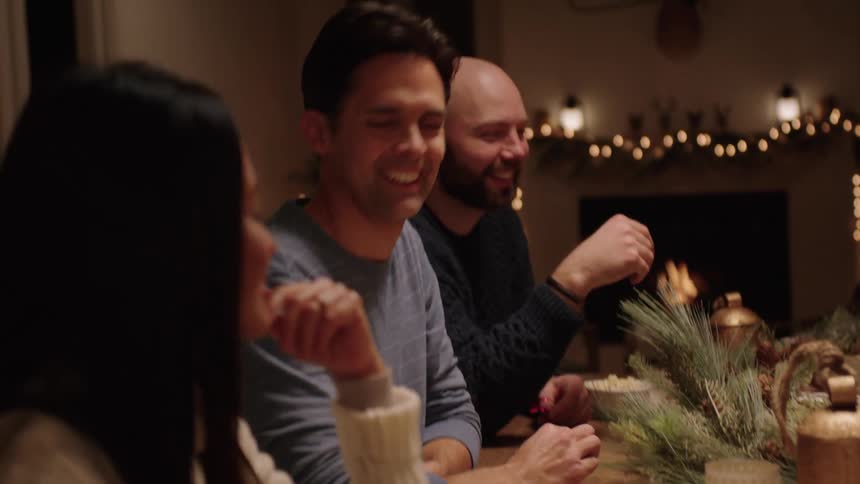 A family wrapping christmas presents on a wooden table