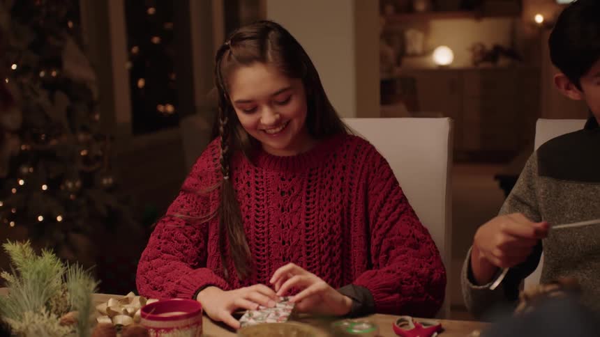 Young girl taking a masking tape handed to her by her father and closing a gift package