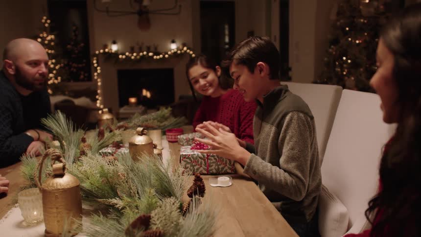 Happy family gather in the dining room to wrap christmas gifts