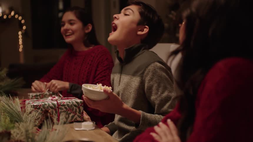 Family have fun playing with popcorn while wrapping christmas gifts