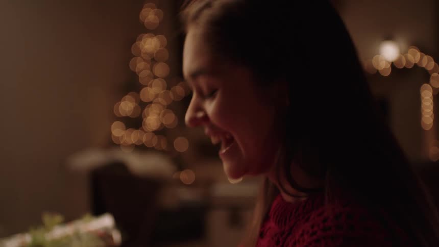 Teenage girl laughs and smiles surrounded by christmas decorations