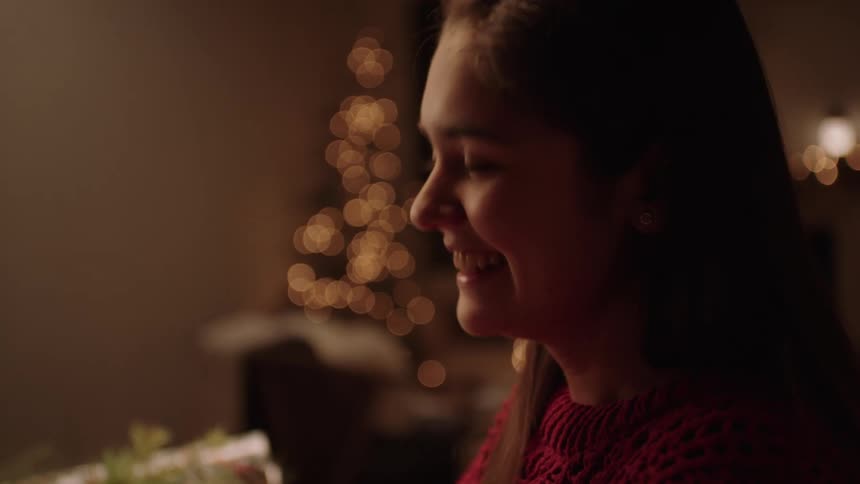 Happy teenage girl wrapping gifts on christmas night
