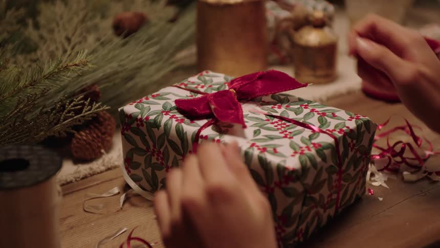 A person wrapping a christmas present on a table