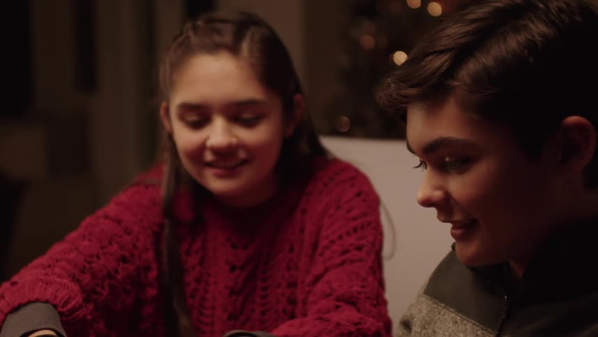 Portrait of two brothers sitting at the table opening a gift and happy
