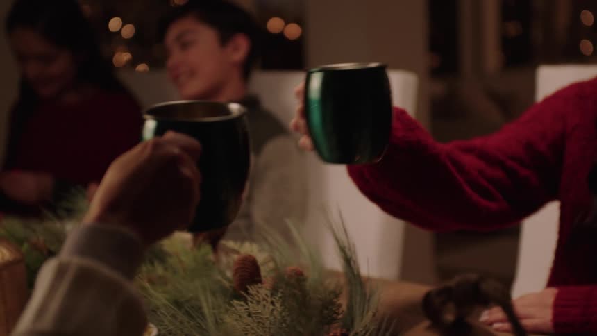 Family gathered at the table at christmas toast with warm drinks