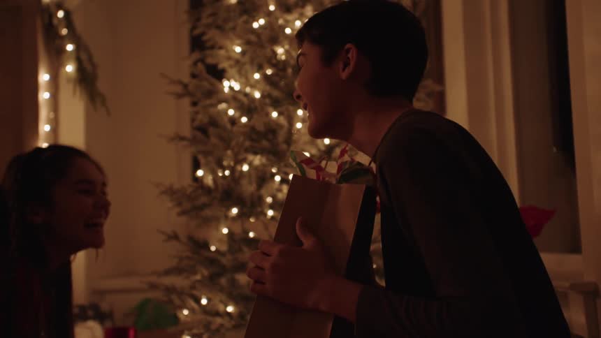 A brother and sister laugh over christmas presents