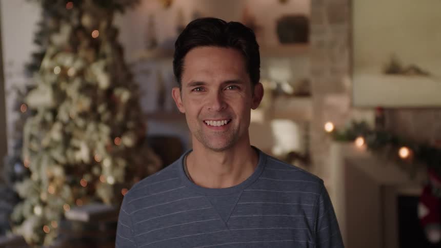 A man smiling in a room decorated with christmas decorations