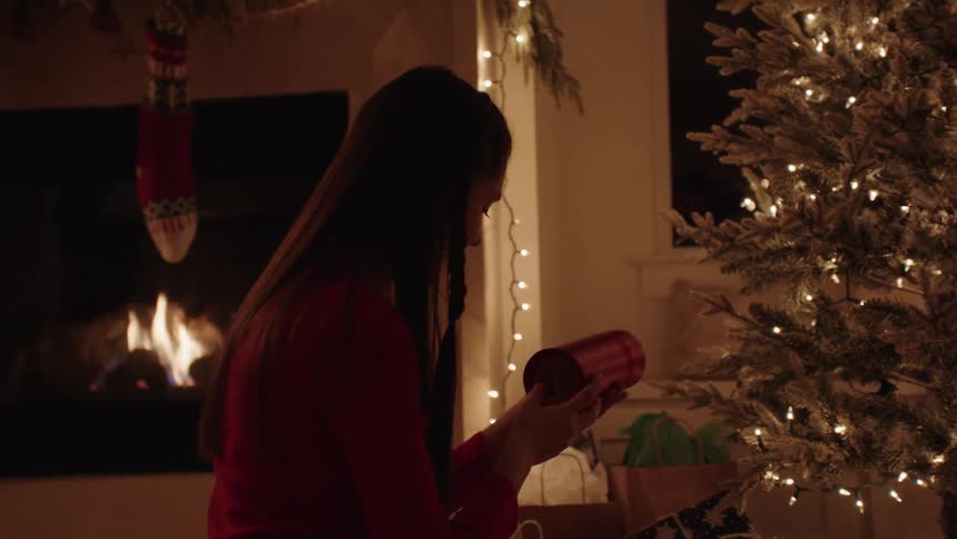Boy and girl checking their christmas gifts while kneeling indoor at night