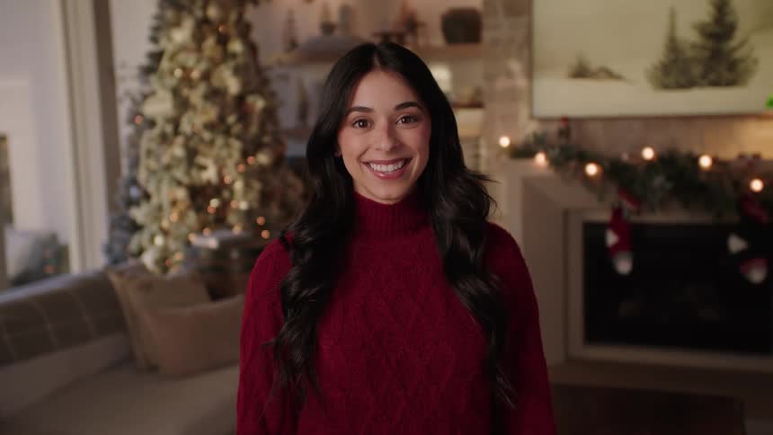 A smiling woman in a room decorated for christmas