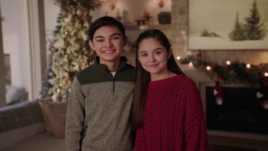 Smiling Siblings Embracing in a Cozy Living Room Decorated for Christmas