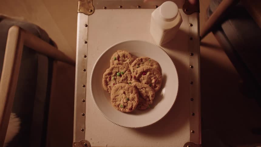 People place a plate of cookies and a bottle of milk on the small table