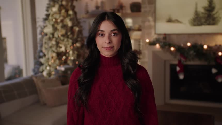 A woman with dark hair stands in a living room