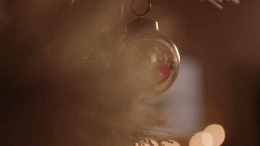 A reflection of a young girl is seen in a Christmas ornament