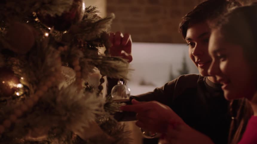 A young boy and girl decorate a Christmas tree
