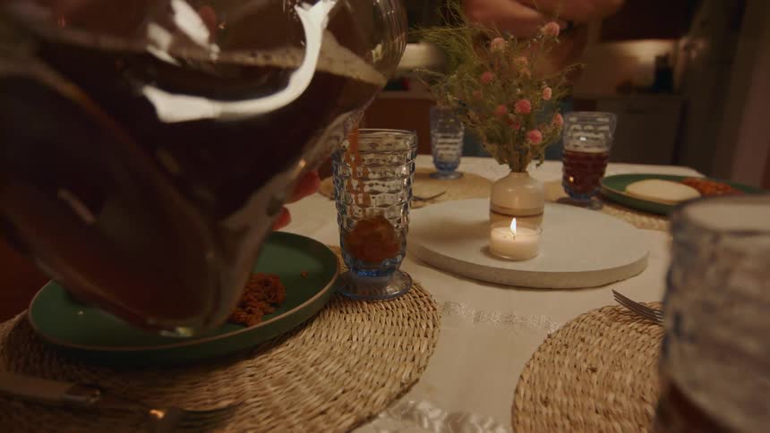 Man stands waiting while another person fills glass sitting on place mat near plate of food