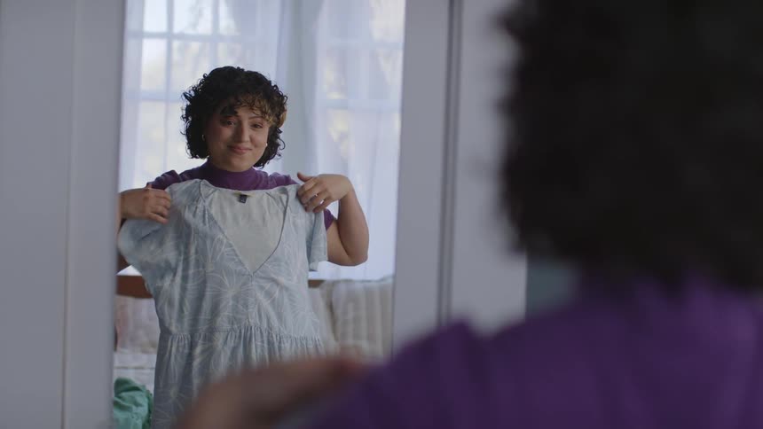 A woman in front of the mirror chooses an outfit to wear