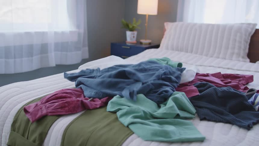 Pieces of clothing being thrown on a bed