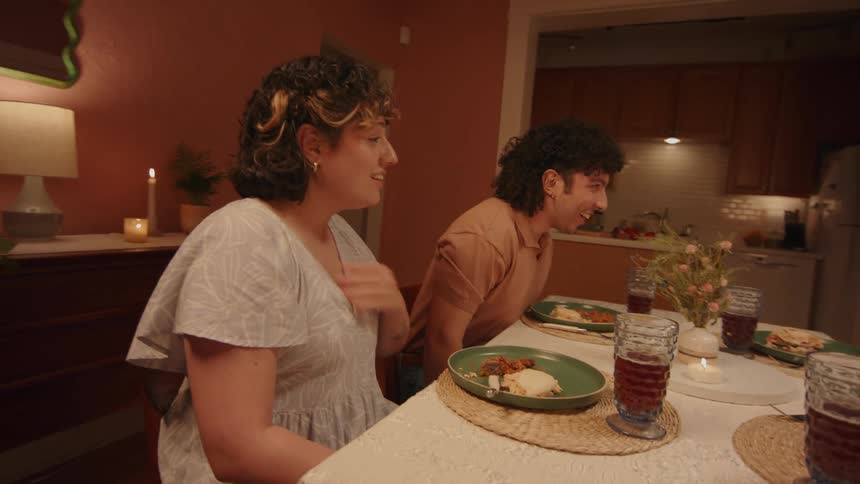 Two couples are sitting at a table full of dishes and drinks and they are all talking happily